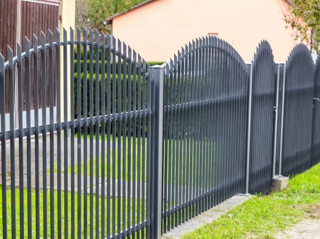 Arched black wrought iron fence and gates with vertical pickets for residential property security.