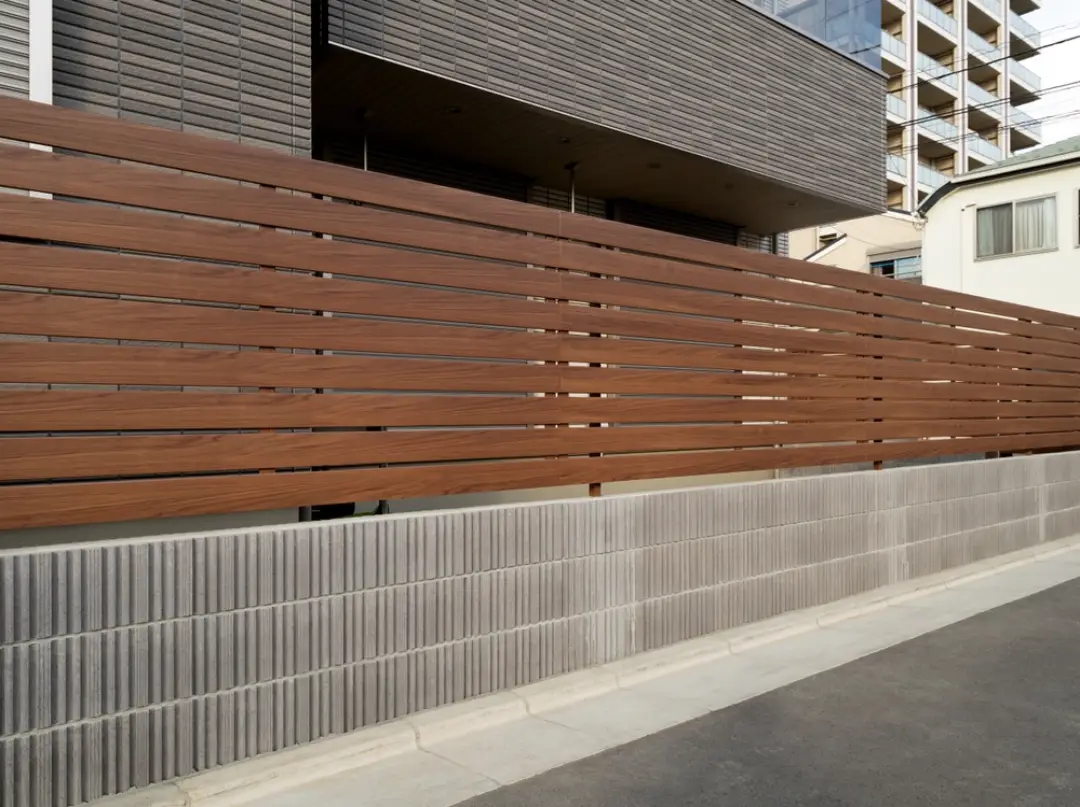 Modern horizontal wood plank fence and gates installed in front of a contemporary home with dark trim.