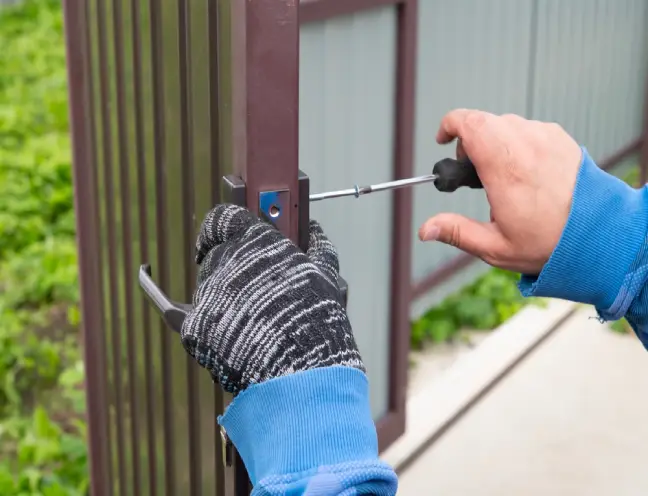 Close-up of a professional contractor installing secure locking hardware on a custom gates system.