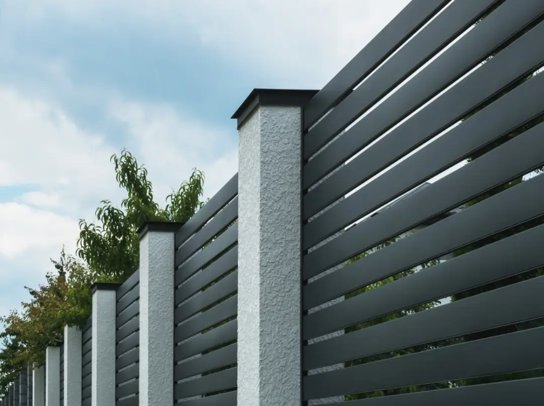 Sleek dark gray horizontal aluminum slat fence and gates with white architectural pillars.